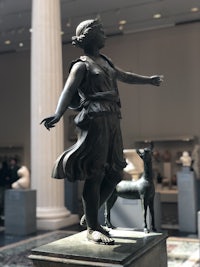 a statue of a woman and a dog in a museum
